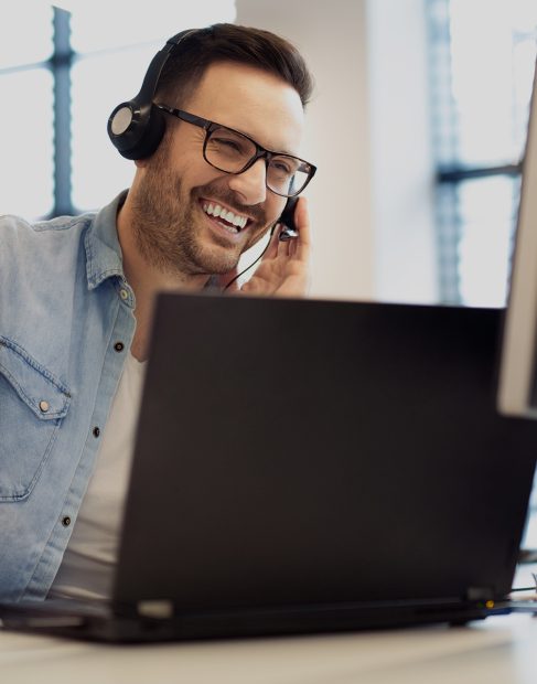 A male call center operator is talking on a phone to a customer.